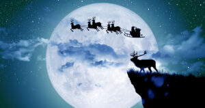 photo of Santa Claus riding with his reindeer through the sky lit by moonlight